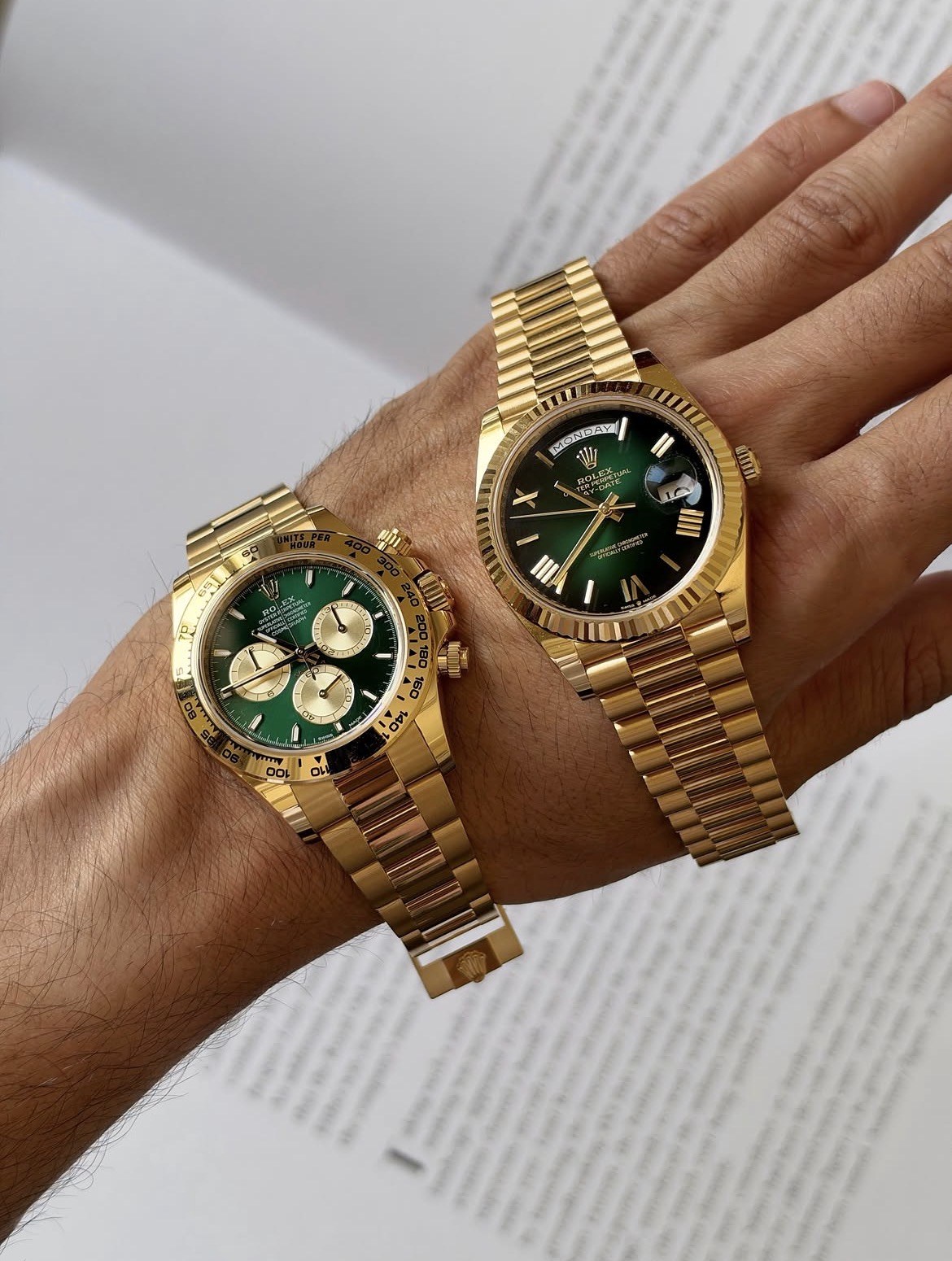 Two gold Rolex watches with green dials on a wrist